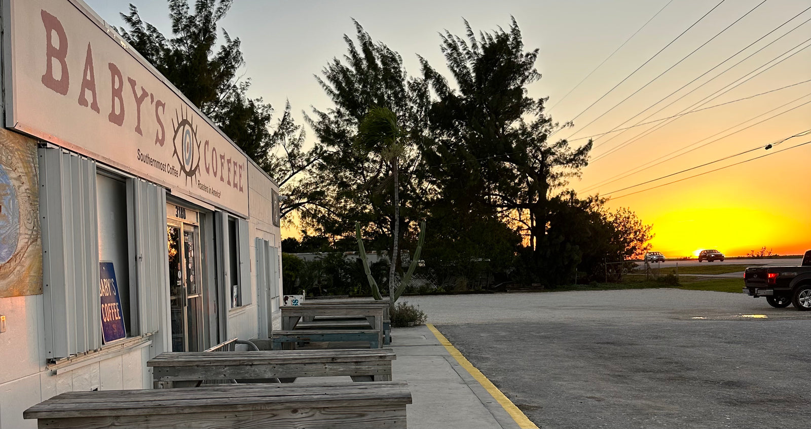 The original Baby’s Coffee storefront and outdoor picnic tables beside US 1 at sunset